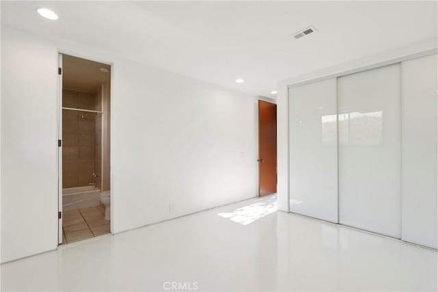 unfurnished bedroom featuring recessed lighting, ensuite bath, a closet, and visible vents