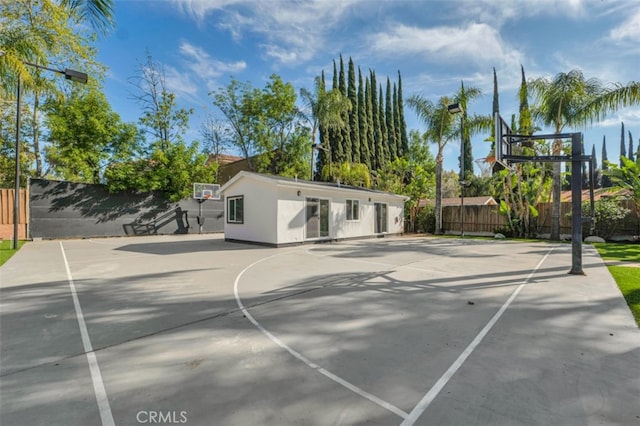 view of basketball court with fence and basketball hoop