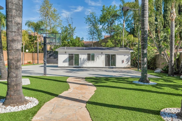 rear view of property with stucco siding, fence, and a yard