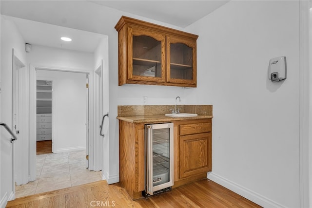 bar featuring a sink, wine cooler, wet bar, and light wood finished floors