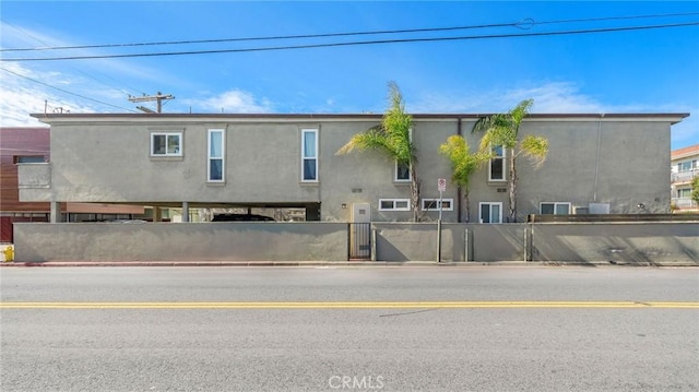 rear view of property featuring stucco siding and a fenced front yard