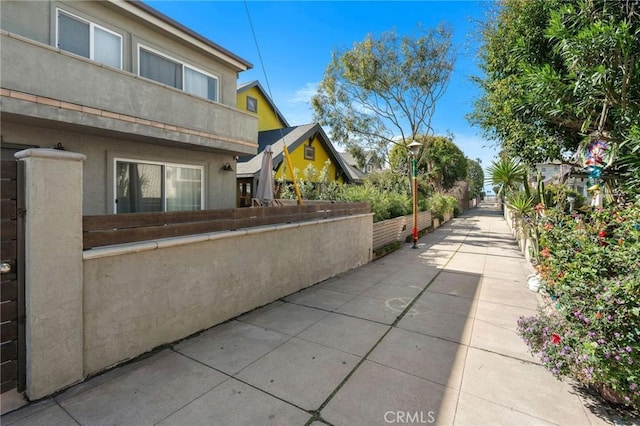 view of side of home featuring stucco siding and fence