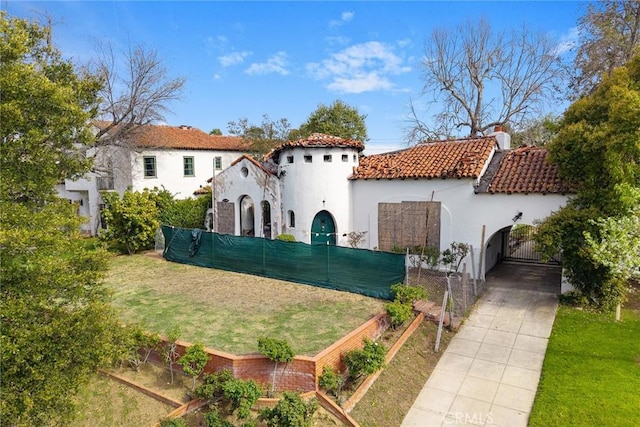 view of front of house with fence, a gate, a tiled roof, and stucco siding