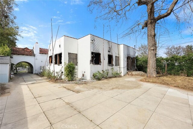 view of front of property with a gate, driveway, and stucco siding