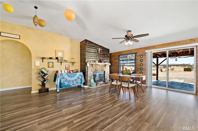 living area with baseboards, a large fireplace, wood finished floors, and a ceiling fan
