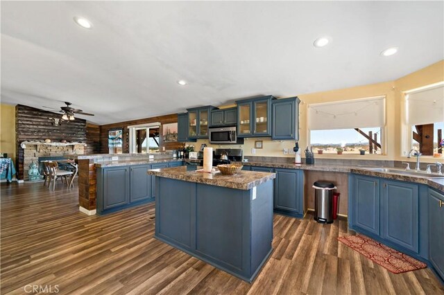 kitchen featuring a sink, a peninsula, stove, stainless steel microwave, and ceiling fan