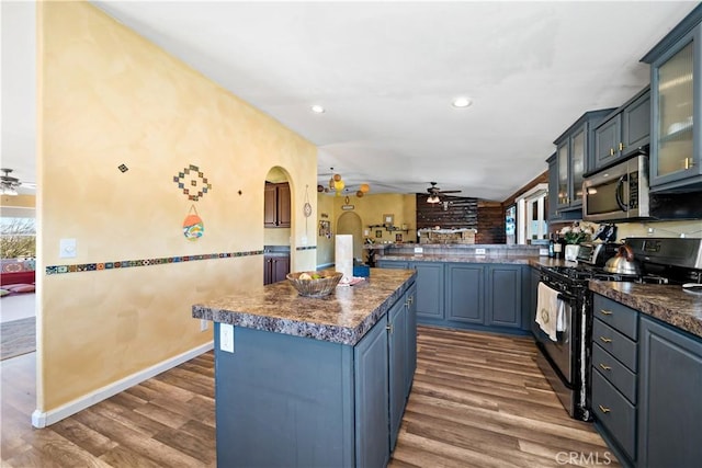 kitchen with stainless steel microwave, a ceiling fan, black gas range oven, and dark wood finished floors
