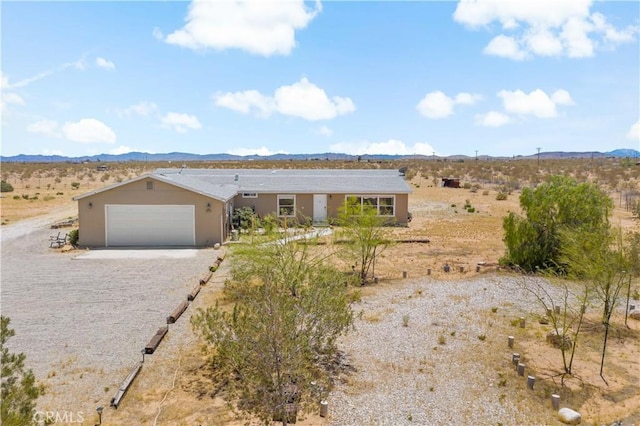 single story home with a desert view, driveway, stucco siding, and a mountain view