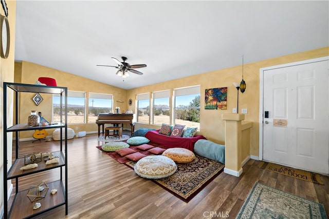 living room with a ceiling fan, baseboards, lofted ceiling, and wood finished floors