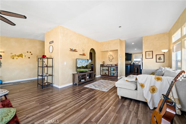 living room with wood finished floors, lofted ceiling, baseboards, arched walkways, and ceiling fan