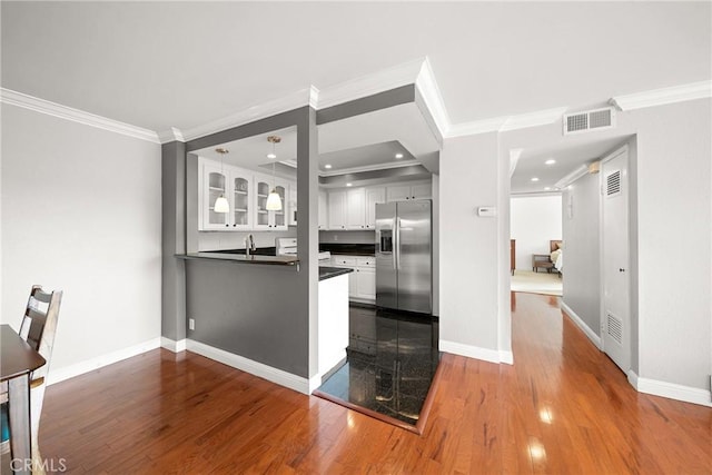 kitchen featuring white cabinetry, stainless steel fridge with ice dispenser, dark countertops, dark wood-style floors, and visible vents