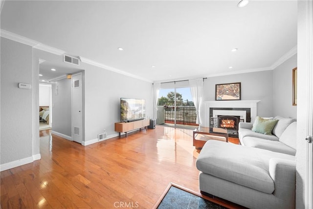 living room featuring wood finished floors, crown molding, baseboards, and visible vents