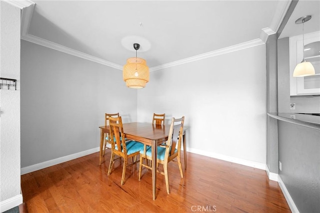 dining space featuring crown molding, baseboards, and wood finished floors