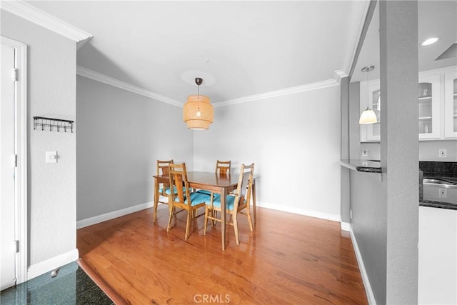 dining room with baseboards, crown molding, and wood finished floors