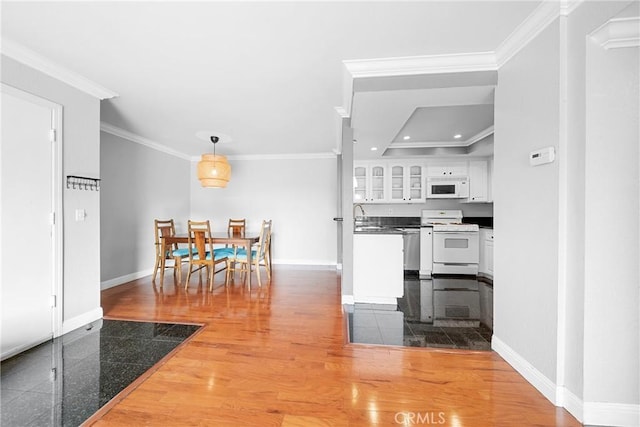 kitchen featuring white cabinetry, white appliances, ornamental molding, baseboards, and glass insert cabinets