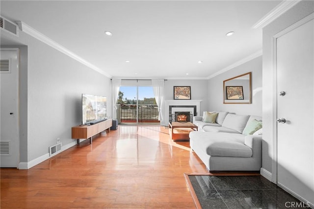 living room featuring baseboards, visible vents, crown molding, and wood finished floors