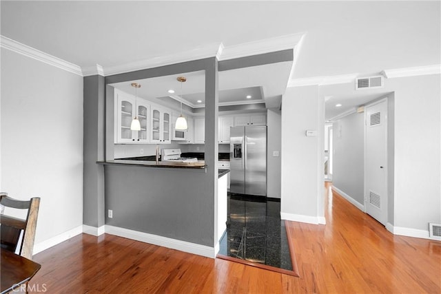 kitchen with white cabinetry, glass insert cabinets, dark countertops, white appliances, and visible vents