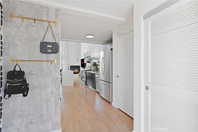 4215 Glencoe Ave Unit 407, Marina Del Rey, CA 90292 - kitchen featuring light countertops, stainless steel appliances, under cabinet range hood, a lit fireplace, and light wood finished floors
