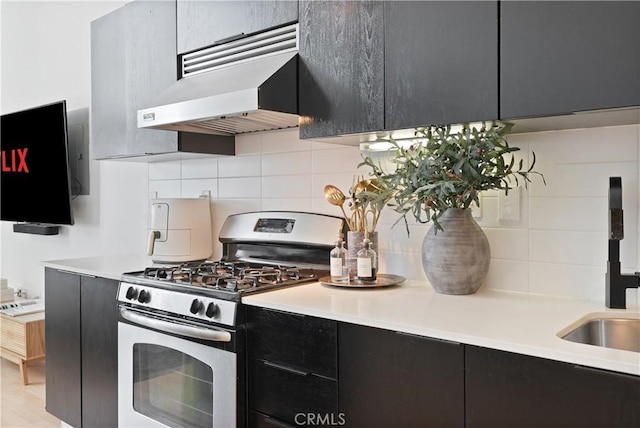 4215 Glencoe Ave Unit 407, Marina Del Rey, CA 90292 - kitchen featuring light countertops, stainless steel gas range oven, dark cabinets, under cabinet range hood, and decorative backsplash