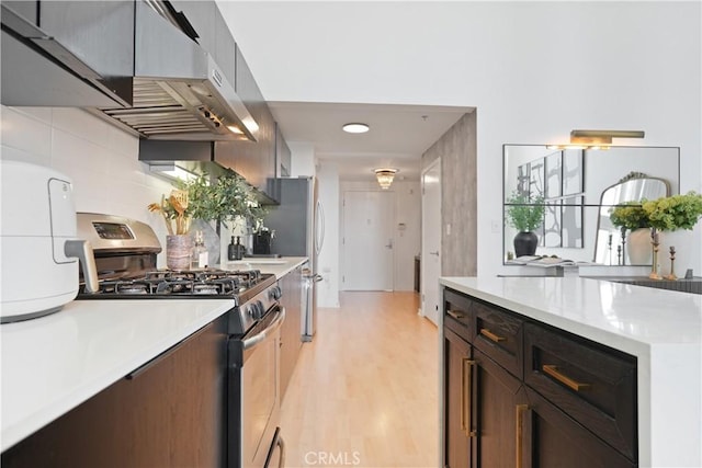 4215 Glencoe Ave Unit 407, Marina Del Rey, CA 90292 - kitchen featuring light countertops, stainless steel gas range oven, under cabinet range hood, backsplash, and light wood-style flooring