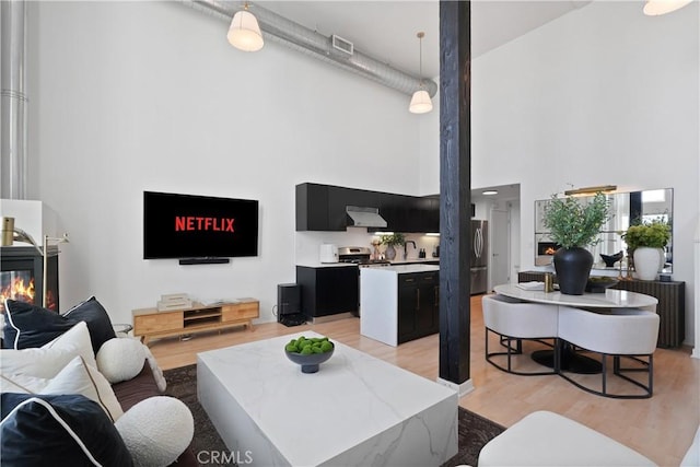 4215 Glencoe Ave Unit 407, Marina Del Rey, CA 90292 - living area featuring a towering ceiling, a glass covered fireplace, and light wood-style floors