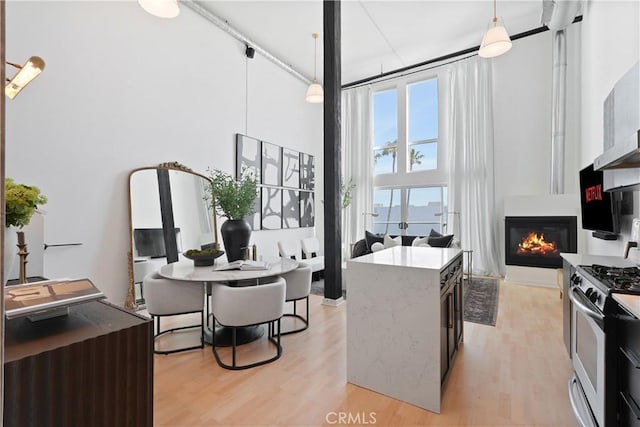4215 Glencoe Ave Unit 407, Marina Del Rey, CA 90292 - kitchen with stainless steel gas range oven, decorative light fixtures, a high ceiling, light wood finished floors, and a fireplace