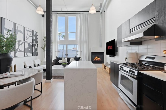 4215 Glencoe Ave Unit 407, Marina Del Rey, CA 90292 - kitchen with a high ceiling, dark cabinetry, gas range, and light wood finished floors