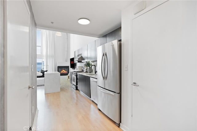 4215 Glencoe Ave Unit 407, Marina Del Rey, CA 90292 - kitchen with light countertops, a sink, a fireplace, appliances with stainless steel finishes, and light wood-style flooring