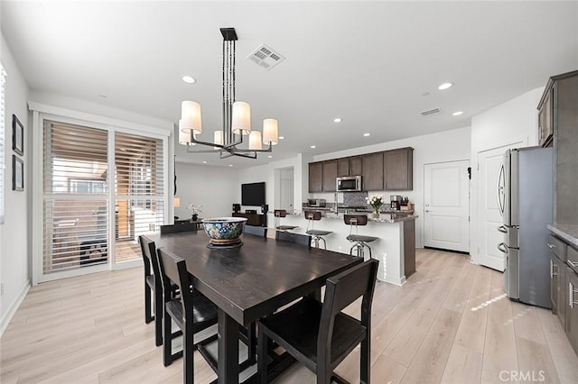 dining space with light wood-style flooring, visible vents, recessed lighting, and a chandelier