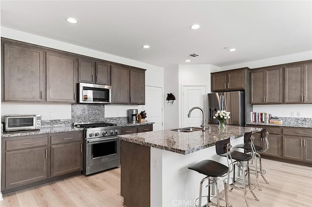 kitchen with a toaster, stone counters, stainless steel appliances, and a sink