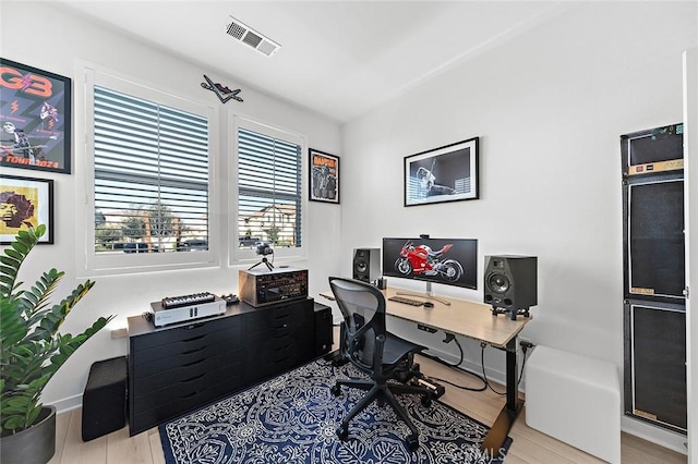 office featuring baseboards, light wood-style floors, and visible vents