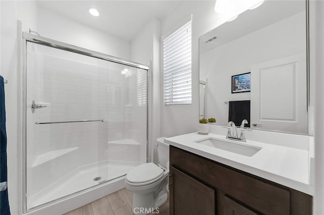 bathroom with toilet, vanity, visible vents, and a stall shower