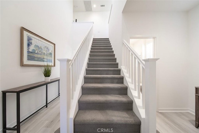 staircase featuring wood finished floors and visible vents