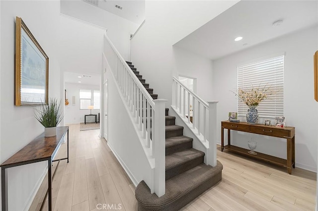 stairs with visible vents, wood finished floors, and recessed lighting