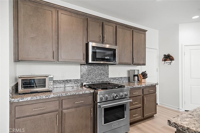 kitchen featuring light stone countertops, stainless steel appliances, and light wood-style flooring