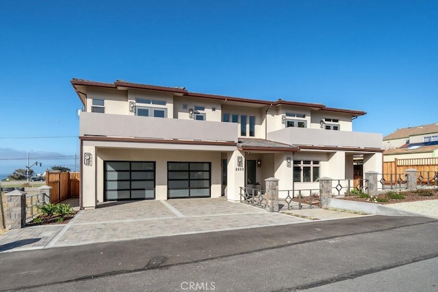 prairie-style home featuring driveway, stucco siding, fence, an attached garage, and a balcony