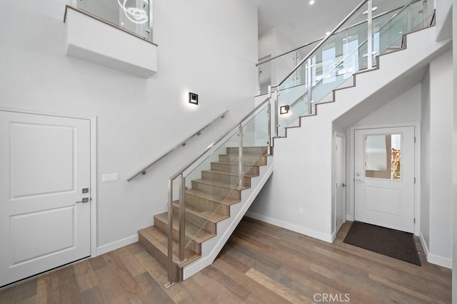 stairs with a high ceiling, baseboards, and wood finished floors