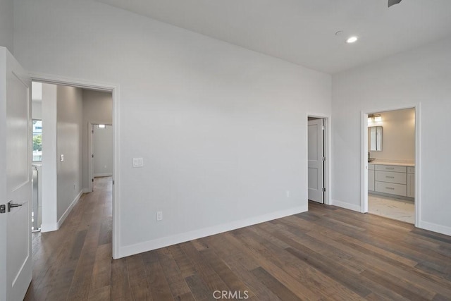unfurnished bedroom featuring baseboards, ensuite bathroom, recessed lighting, and dark wood finished floors