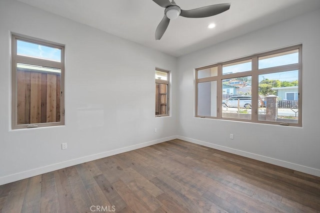 spare room with a ceiling fan, dark wood-style floors, and baseboards