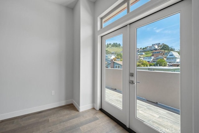 doorway to outside with baseboards, wood finished floors, and french doors