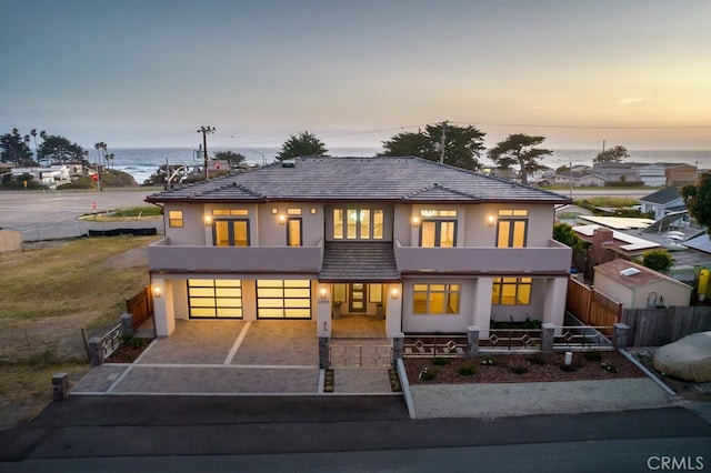 view of front of home featuring stucco siding, fence, a tiled roof, driveway, and a garage