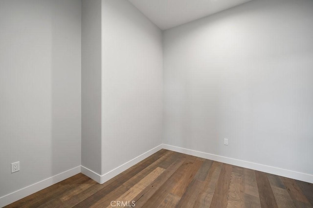 empty room featuring dark wood finished floors and baseboards