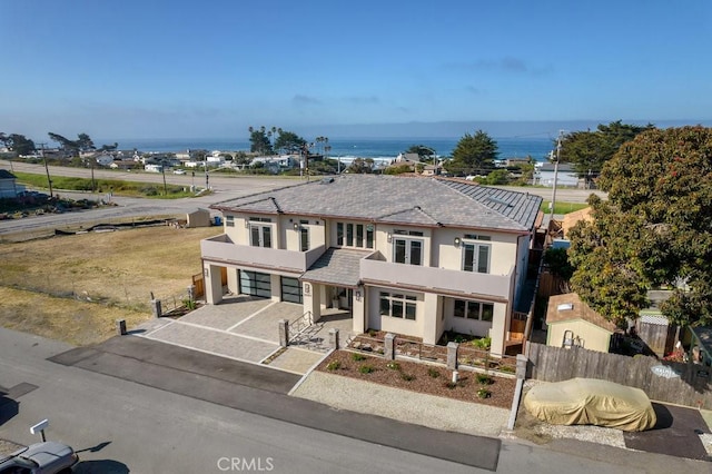 traditional-style home with driveway, a fenced front yard, a garage, and stucco siding