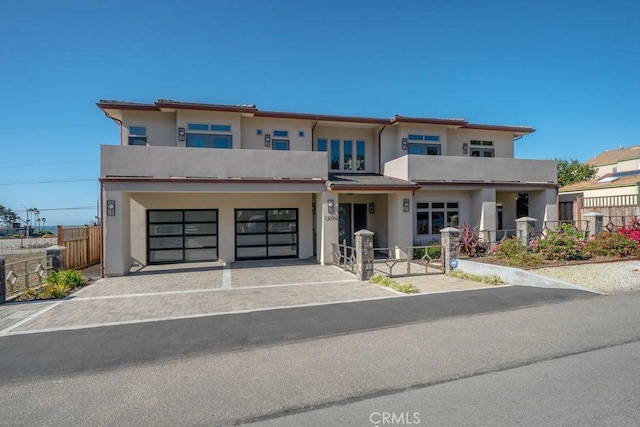 view of front of house featuring fence, driveway, stucco siding, and a garage