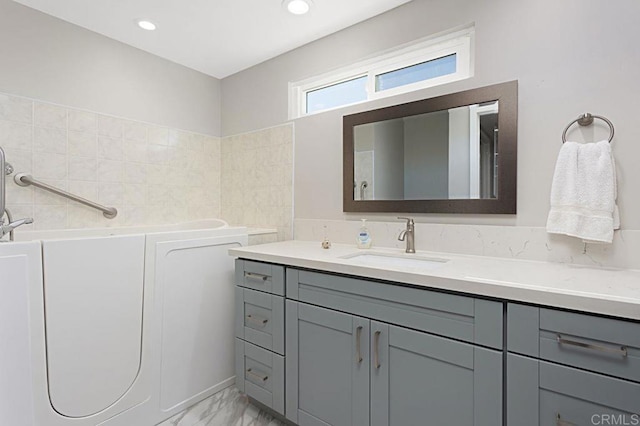 3685 Vista Campana N Unit 72, Oceanside, CA 92057 - bathroom featuring marble look tiles, vanity, and a bath