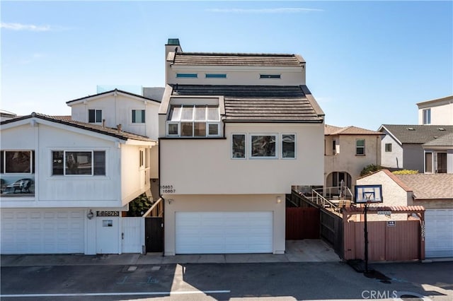 16865 S Pacific Ave, Sunset Beach, CA 90742 - view of front facade with stucco siding, a garage, a gate, and a tile roof
