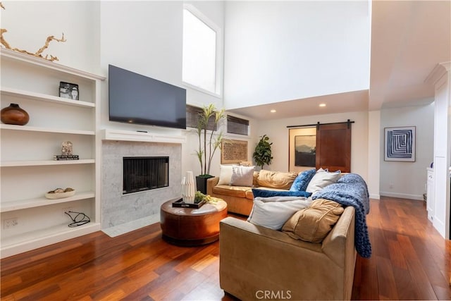 16865 S Pacific Ave, Sunset Beach, CA 90742 - living area with wood finished floors, built in shelves, a high end fireplace, a barn door, and a towering ceiling