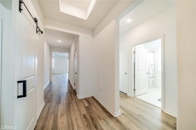 14168 Georgetown St, Hesperia, CA 92344 - corridor featuring a barn door, light wood-style flooring, baseboards, and recessed lighting