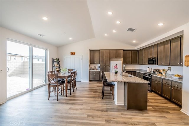 14168 Georgetown St, Hesperia, CA 92344 - kitchen featuring appliances with stainless steel finishes, dark brown cabinetry, lofted ceiling, a sink, and light stone countertops