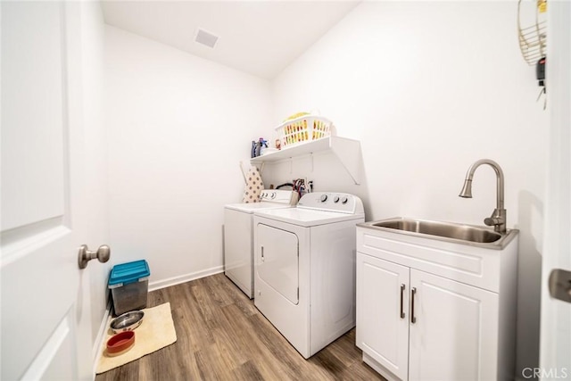 14168 Georgetown St, Hesperia, CA 92344 - laundry room with washing machine and dryer, light wood-type flooring, and cabinet space